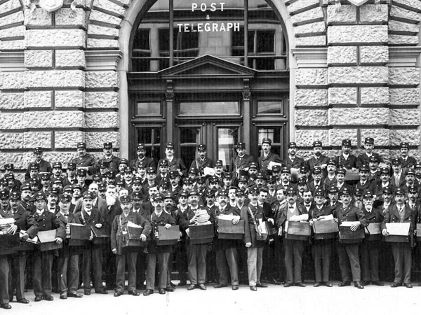 Employés de l’administration postale devant la Fraumünsterpost à Zurich, avec les facteurs au premier rang, vers 1900. Cette catégorie professionnelle conserve elle aussi ses acquis sociaux.