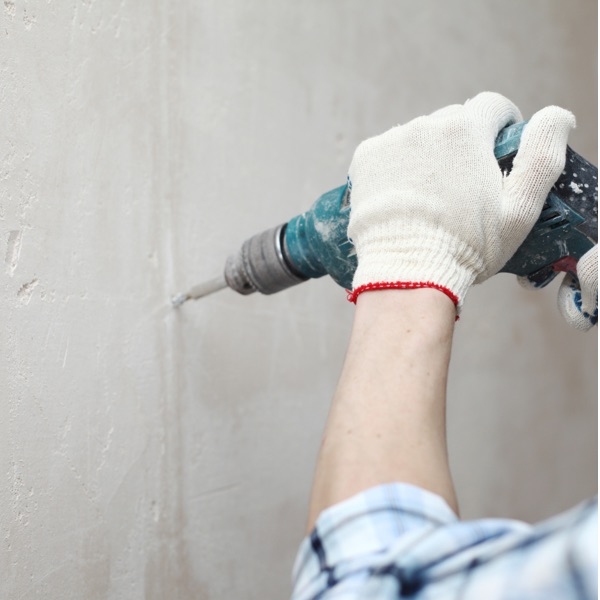 Handwerker bohrt in eine Wand.