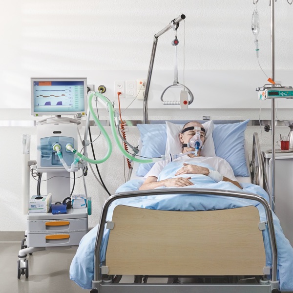Paziente in un letto di ospedale con maschera per l'ossigeno.