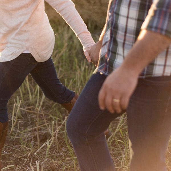 Un couple marche dans un champ en se tenant par la main.
