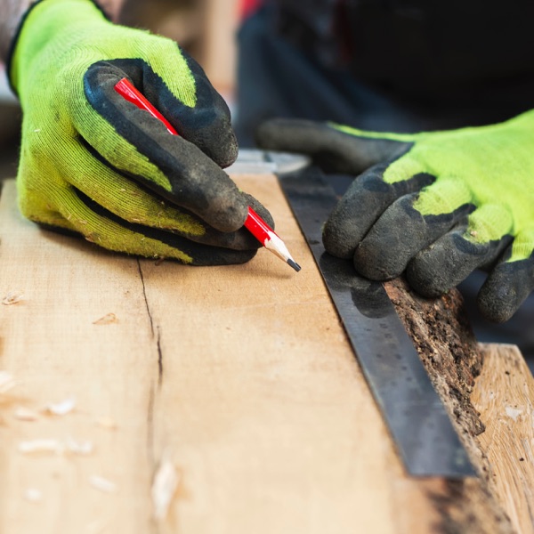 Handwerker macht markierungen auf einem Holzbrett. 